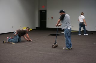 The carpet is being secured to the floor with a roller. 